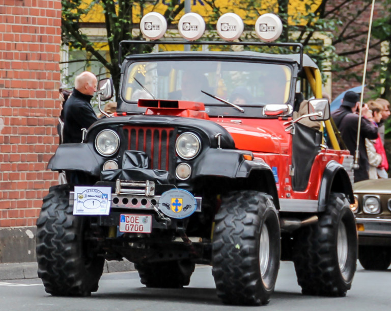 Jeep CJ-5 rouge aux ailes rondes, lors d’un defile de voitures anciennes